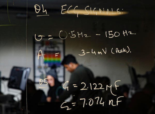 two students working in the Bioinstrumentation Lab, with a clear-screen blackboard in the foreground