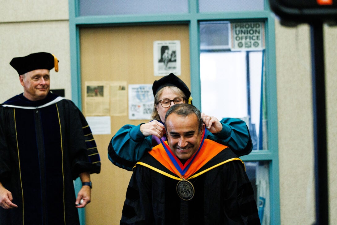 Provost and Vice Chancellor of Academic Affairs Karen Colley places a medal around Robert Uyetani Collegiate Professor Salman Khetani's neck